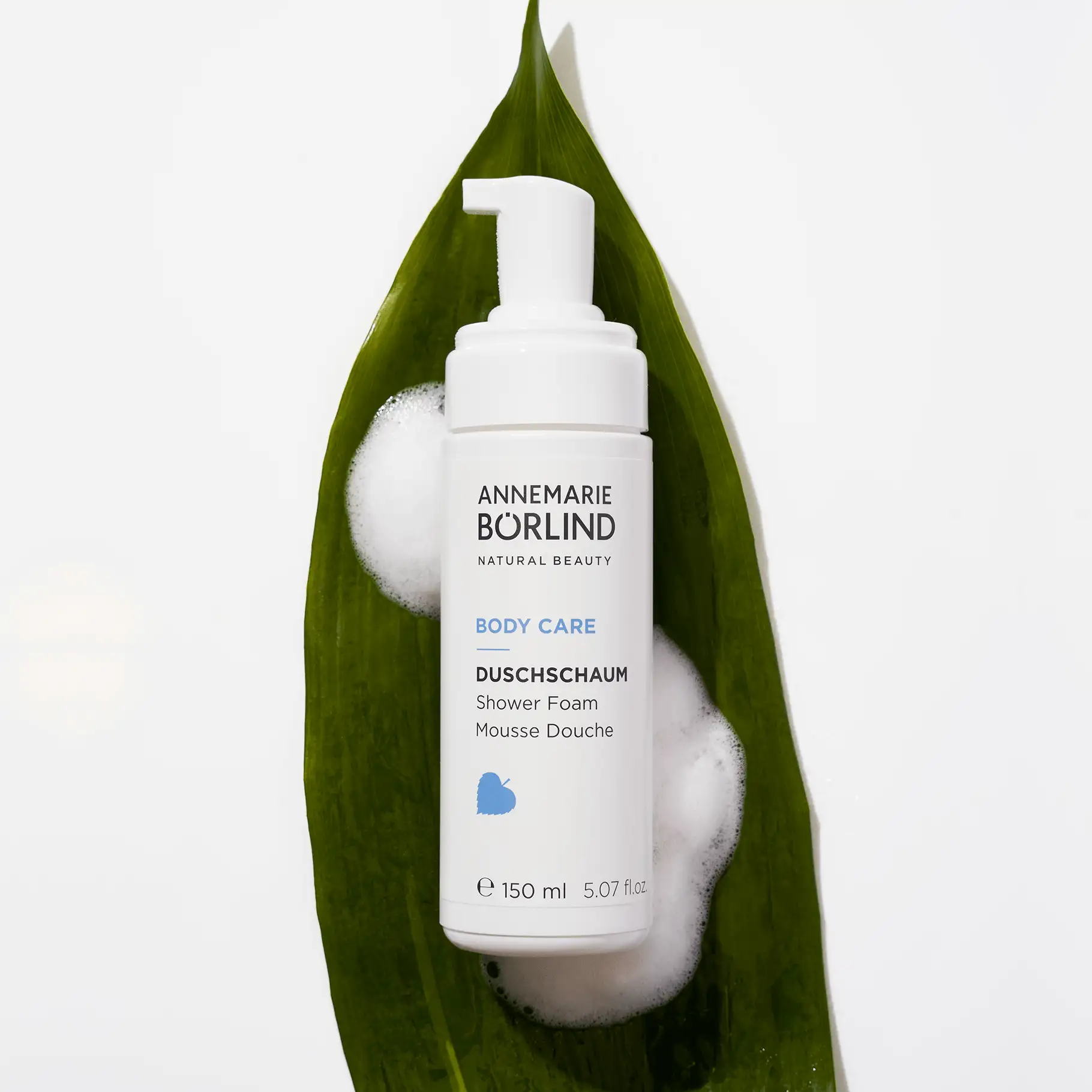 ANNEMARIE BÖRLIND Body Care Duschschaum 150 ml auf grünem Blatt mit weißem Schaum