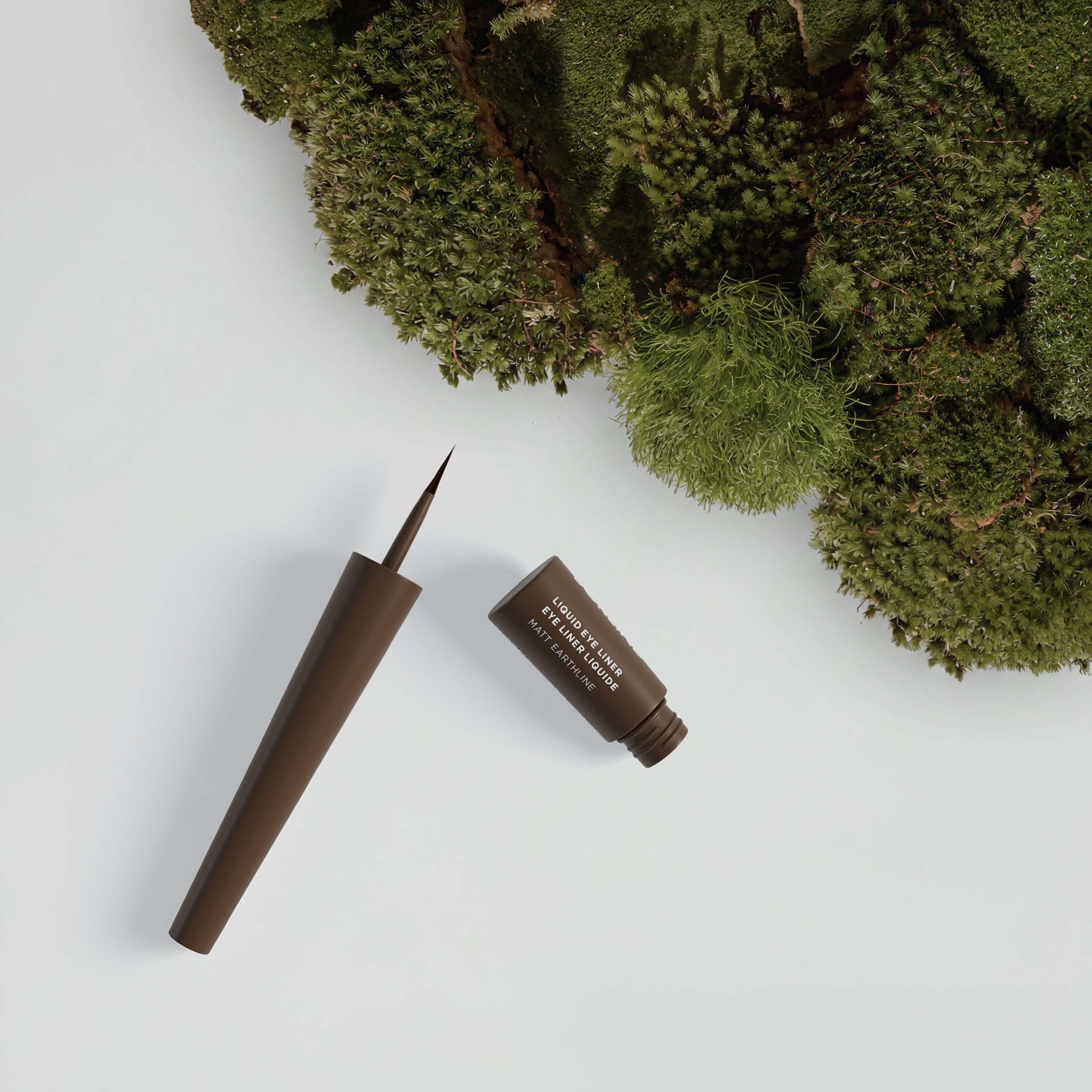 ANNEMARIE BÖRLIND LIQUID EYE LINER Flasche in dunkelbraun neben grünem Moos