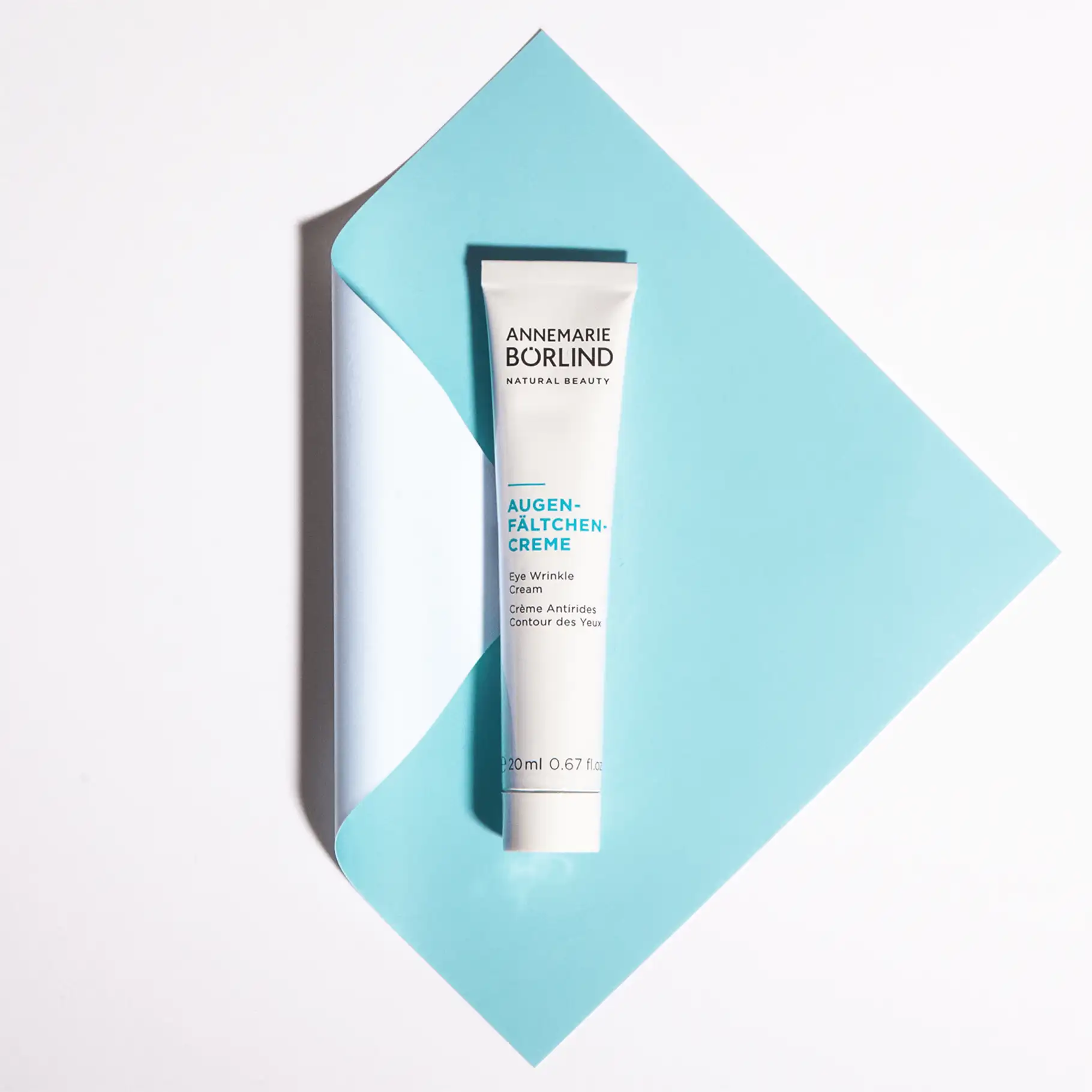 ANNEMARIE BÖRLIND Augen-Fältchen-Creme in weißer Tube auf hellblauem, gefaltetem Papier