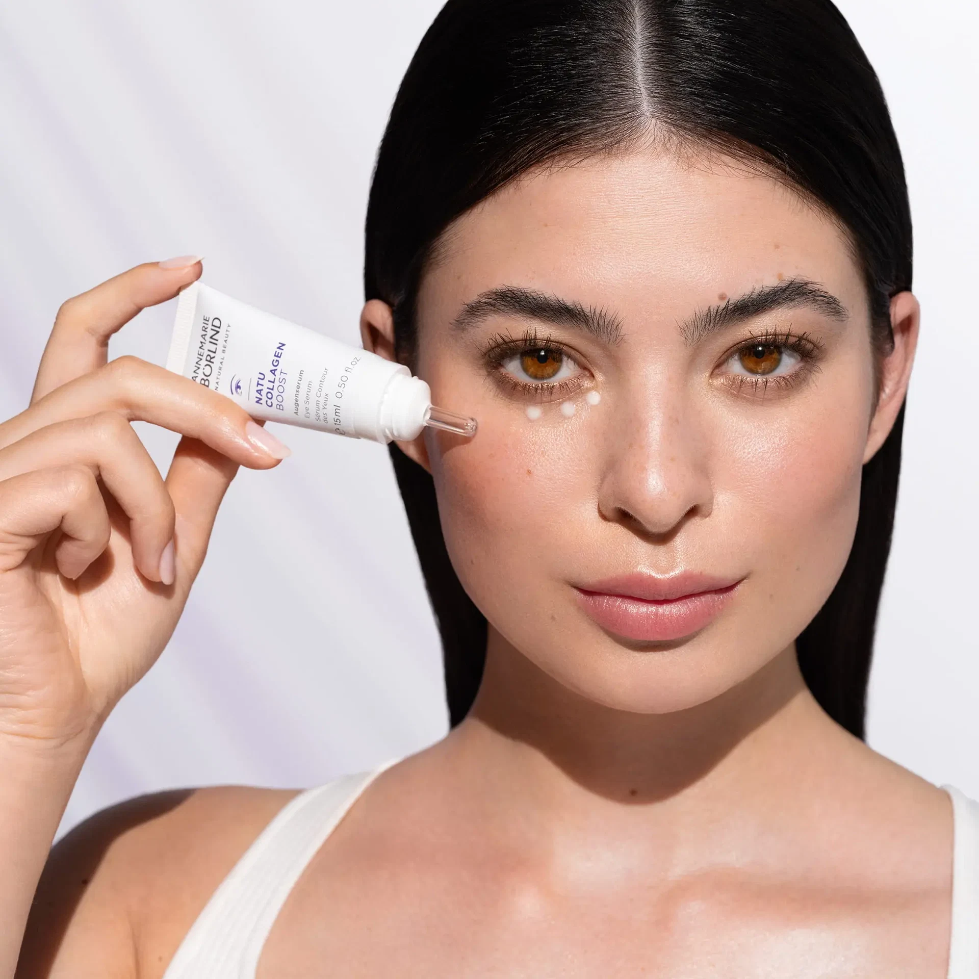 Model trägt NATUCOLLAGEN BOOST Augenserum mit Applikator unter dem Auge auf