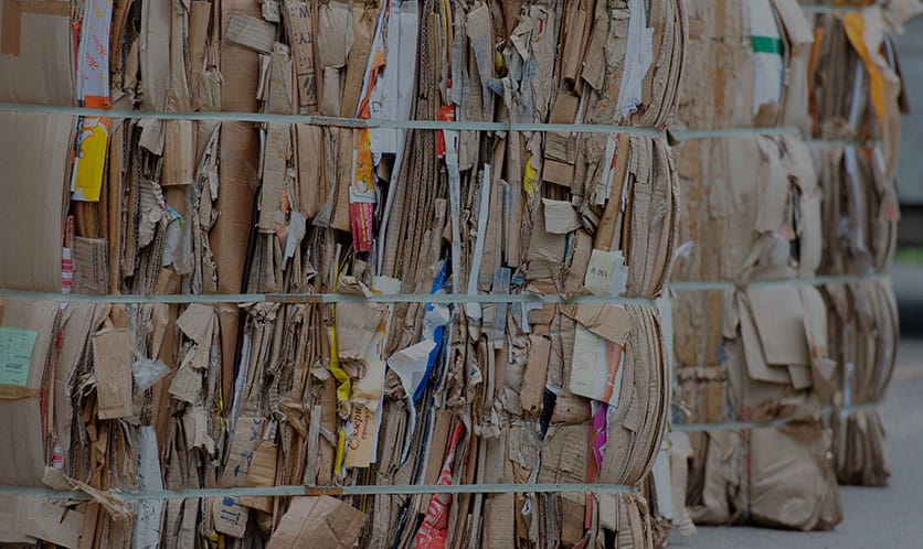 Groß gepresste Pakete aus gebrauchtem Karton und Papier, gebündelt mit Kunststoffbändern auf Lagerfläche