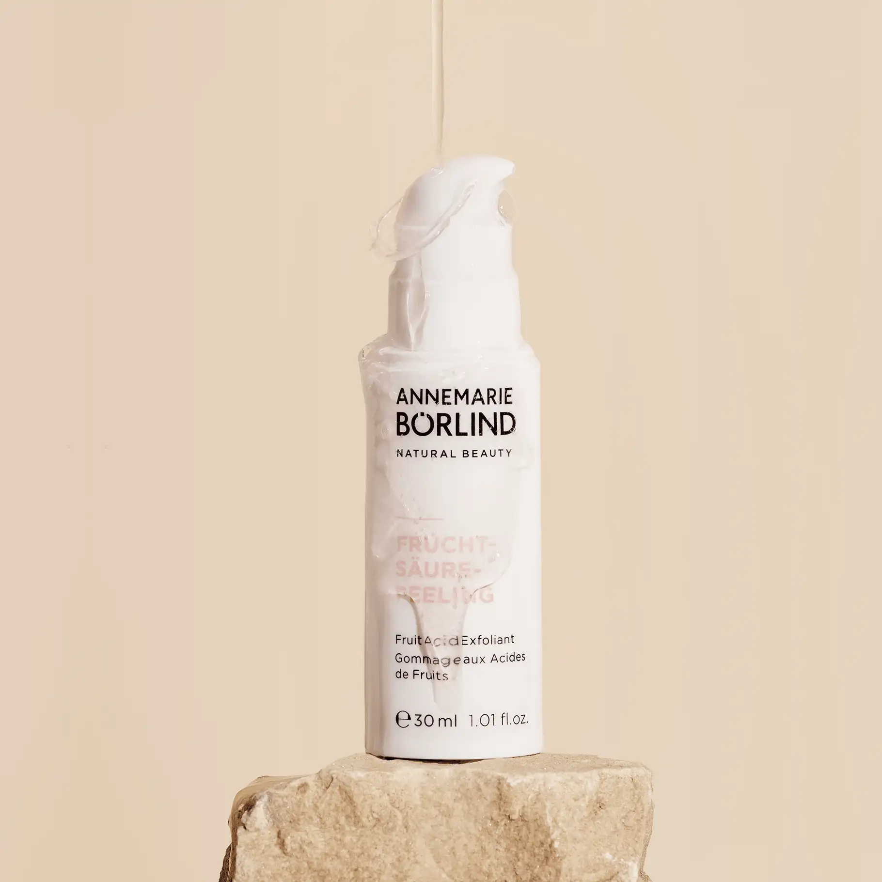 ANNEMARIE BÖRLIND Fruchtsäurepeeling in weißer Flasche mit Pumpspender auf Stein vor beige Hintergrund