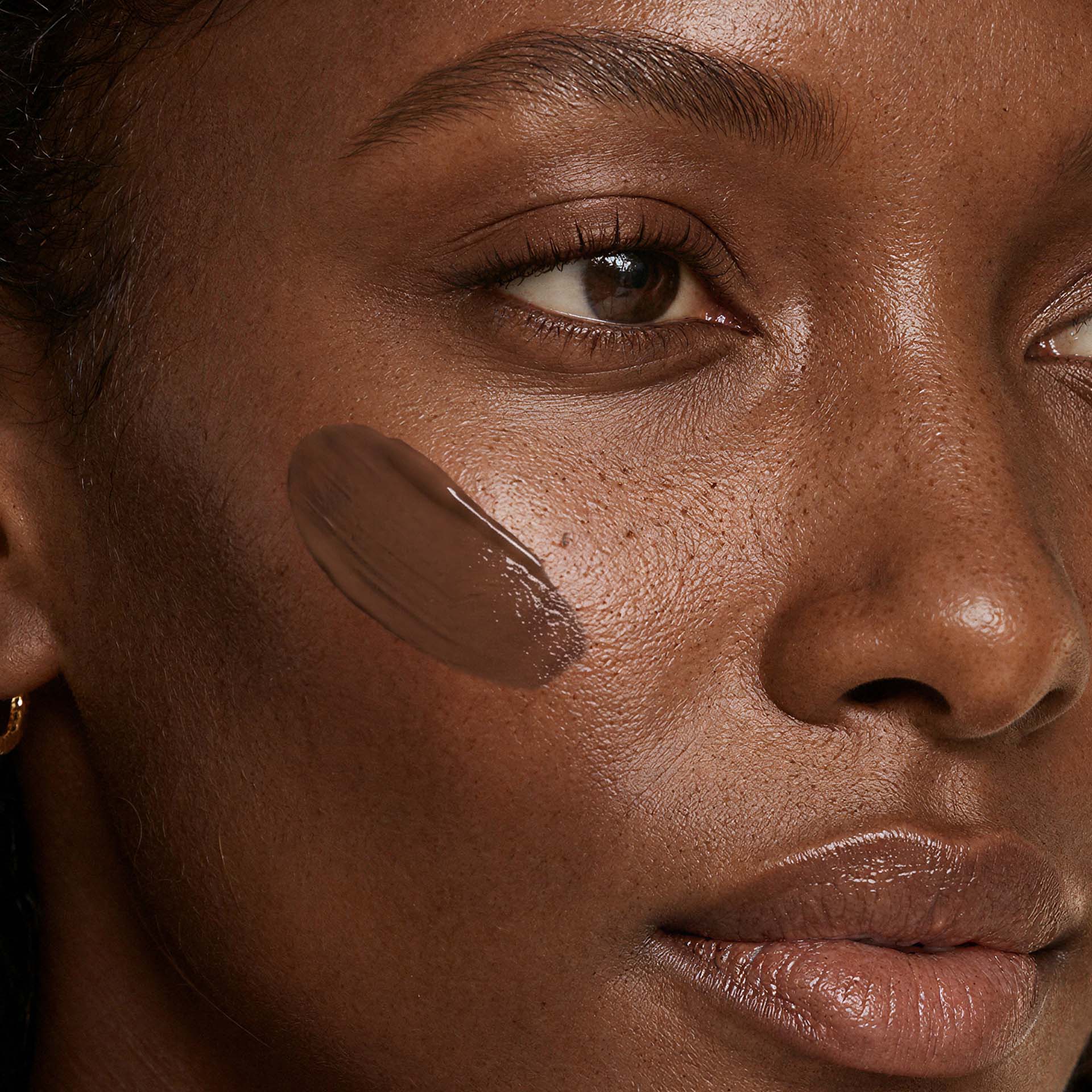 Frau mit dunklerem Teint trägt Anti-Aging Make-up in Walnut auf Wange