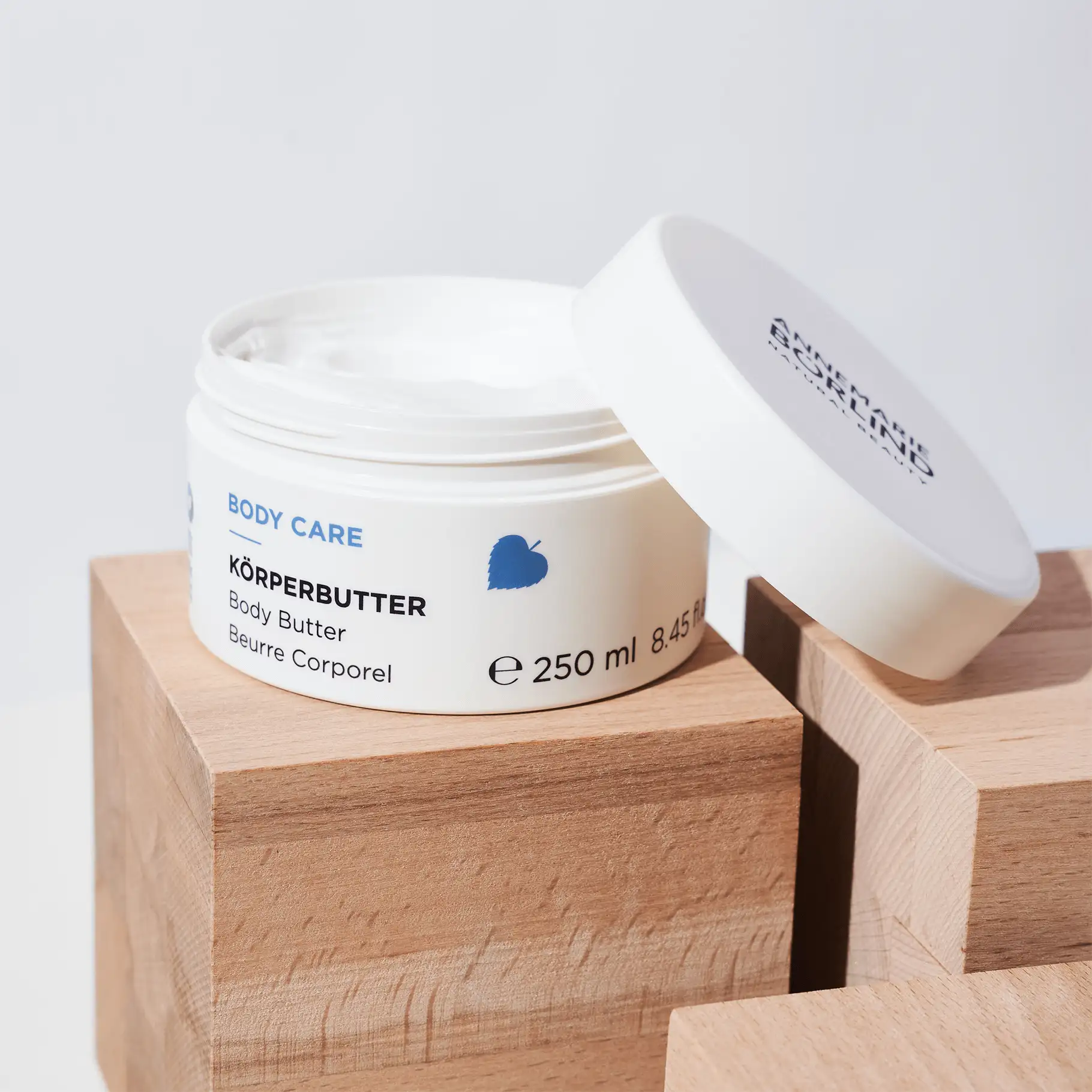 ANNEMARIE BÖRLIND Body Care Körperbutter im offenen weißen Tiegel auf Holzblöcken, 250 ml Inhalt