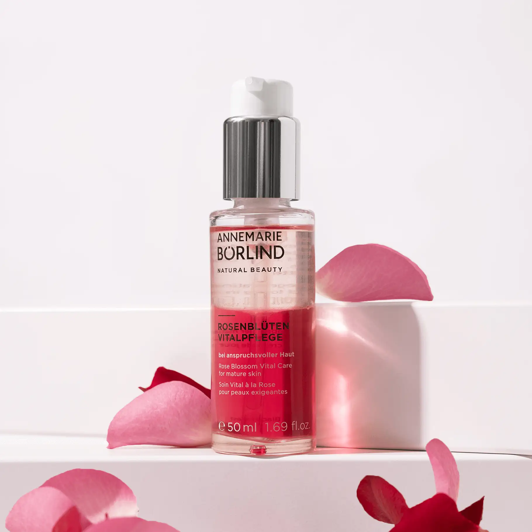 ANNEMARIE BÖRLIND Rosenblüten Vitalpflege Serum in Glasflasche mit silbernem Pumpverschluss und Rosenblütenblättern