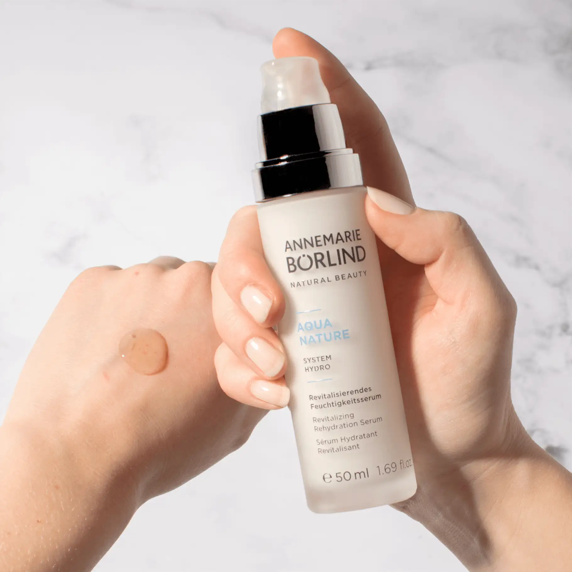 ANNEMARIE BÖRLIND AQUA NATURE revitalisierendes Feuchtigkeitsserum in Hand mit Serumprobe auf Haut