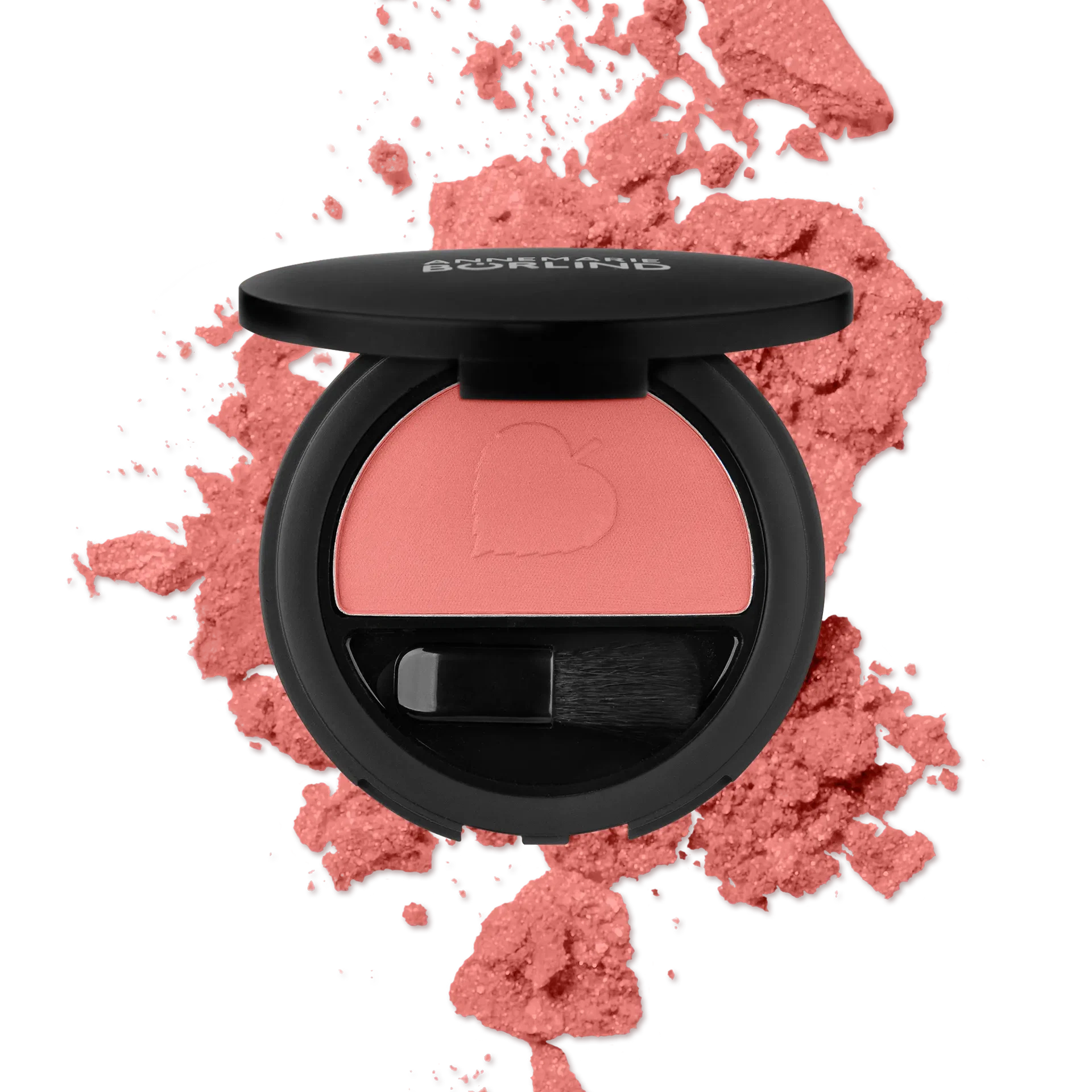 ANNEMARIE BÖRLIND Rouge Coral Glow mit Pinsel in schwarzer runder Dose vor korallfarbenem Puderhintergrund