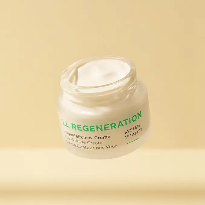 LL REGENERATION Augenfältchen-Creme im geöffneten Tiegel vor beige Hintergrund, cremige Textur sichtbar