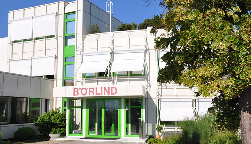 Eingang eines weißen Bürogebäudes mit grünen Fenstern und Türen, Schriftzug BÖRLIND über dem Eingang