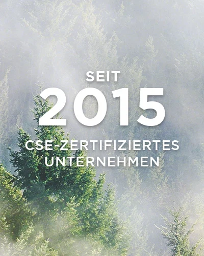 Nebel über grünen Tannen mit Text „Seit 2015 CSE-zertifiziertes Unternehmen“ in weißer Schrift