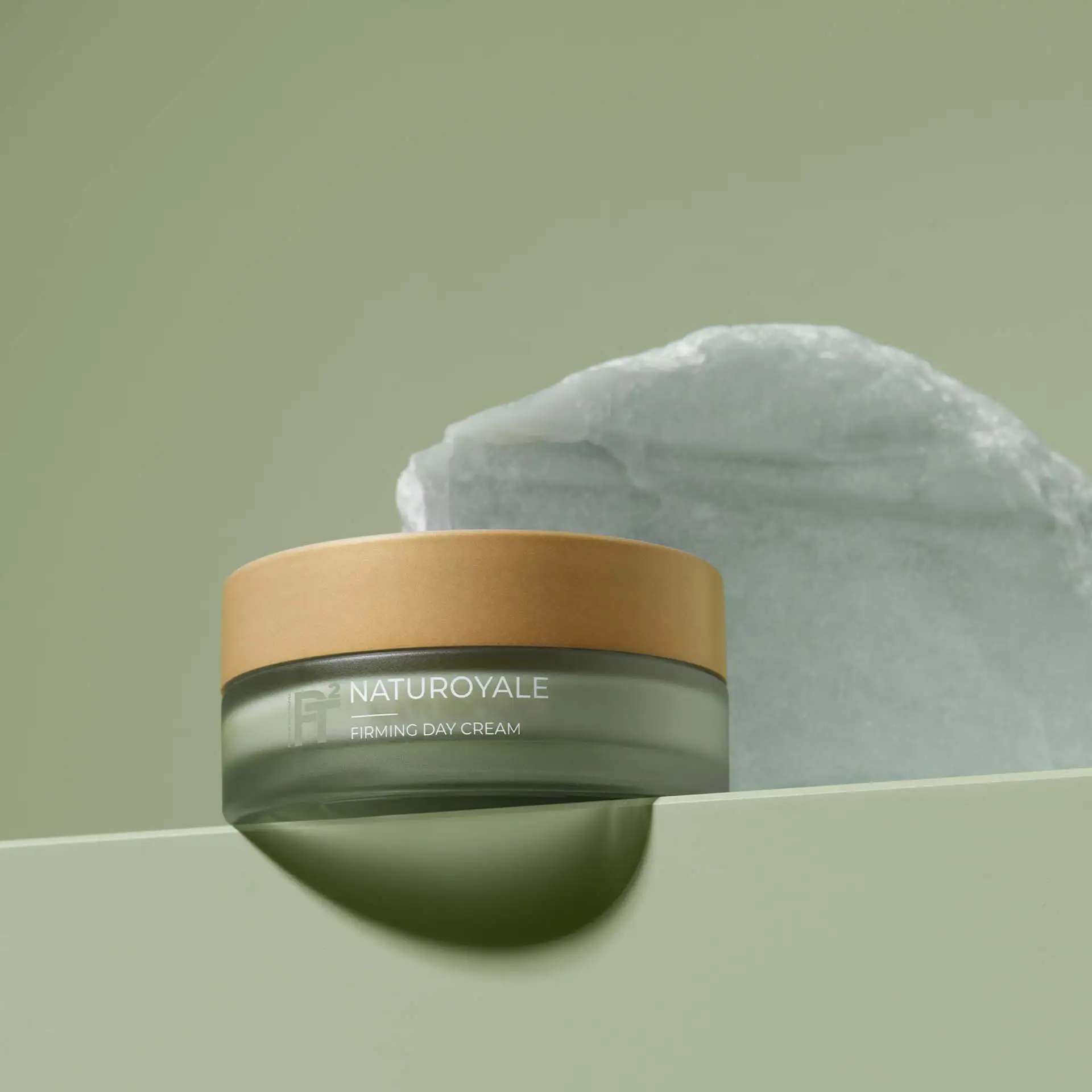 NATUROYALE Firming Day Cream im Glas mit braunem Deckel vor grünem Hintergrund und Steinplatte