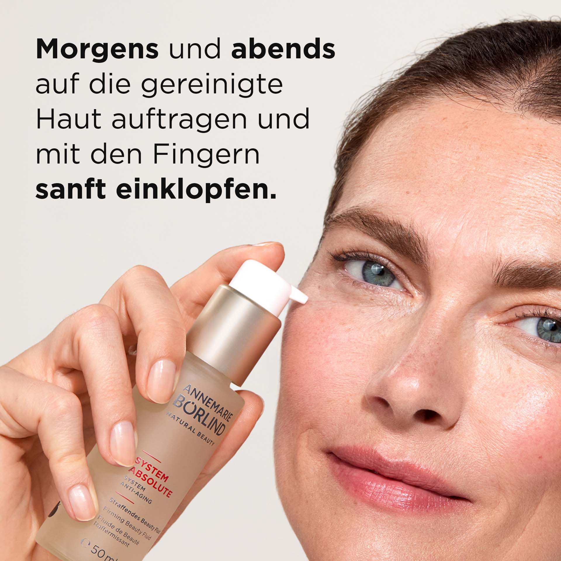 Frau hält SYSTEM ABSOLUTE Straffendes Beauty Fluid vor Gesicht mit Beschreibung