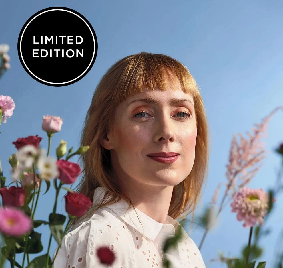 Model mit Season of Bloom Make-up-Look zwischen Blüten vor blauem Hintergrund, mit Hinweis „Limited Edition“