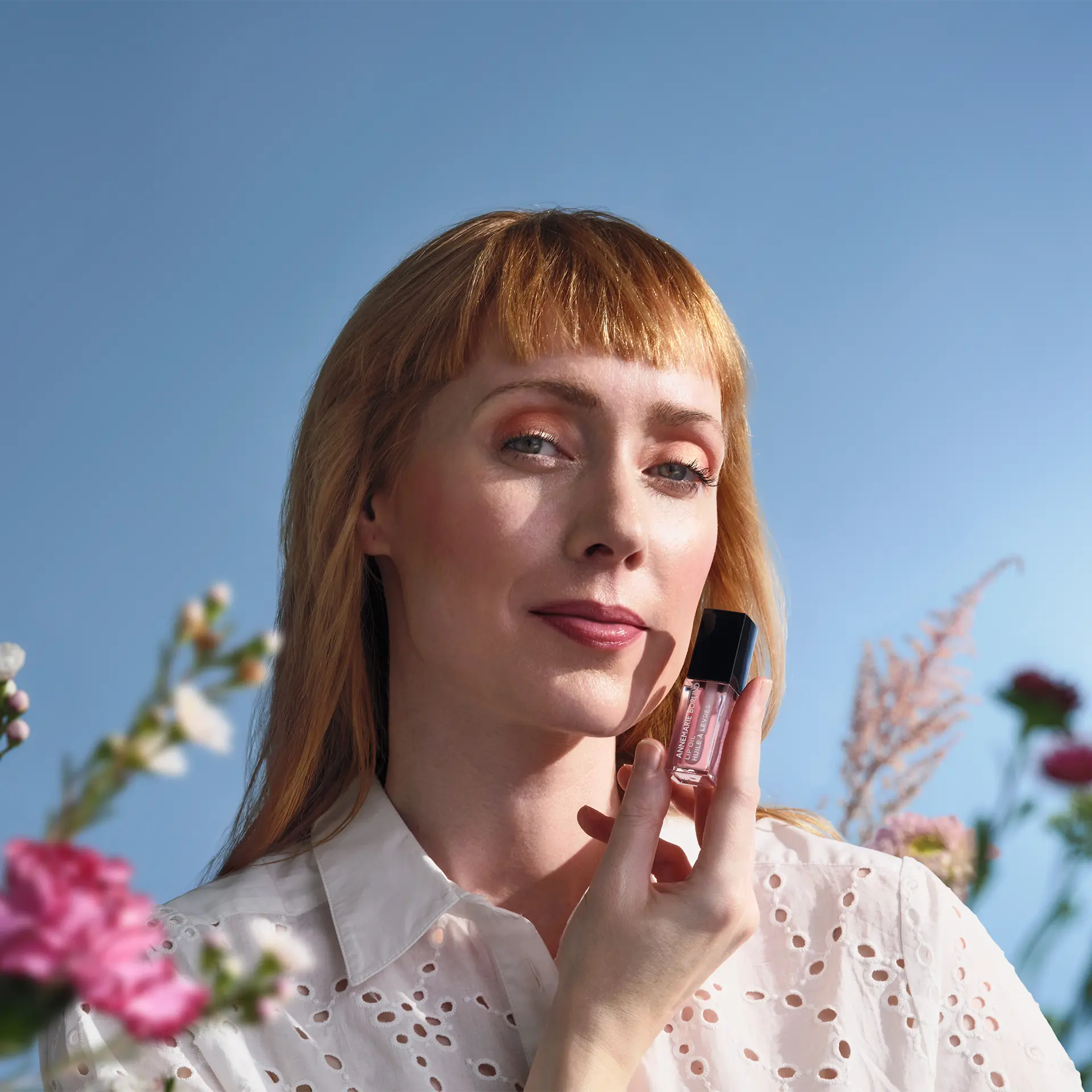 ANNEMARIE BÖRLIND Lip Oil Cherry Blossom vor Gesicht einer Frau mit hellorangenen Haaren