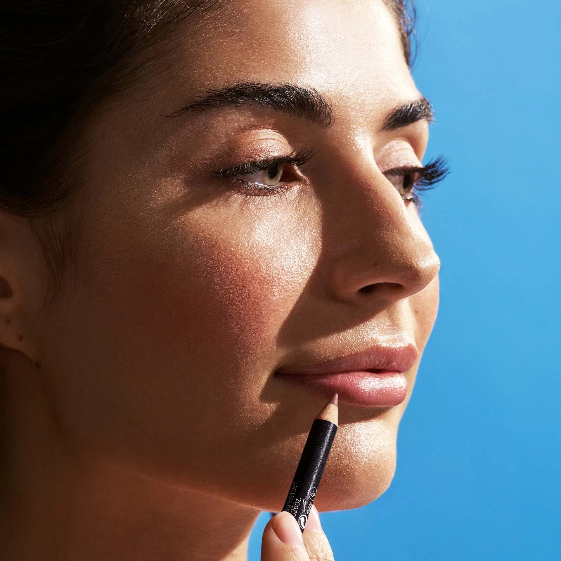 Frau trägt Lippenkonturenstift von ANNEMARIE BÖRLIND auf Lippen auf, blauer Hintergrund