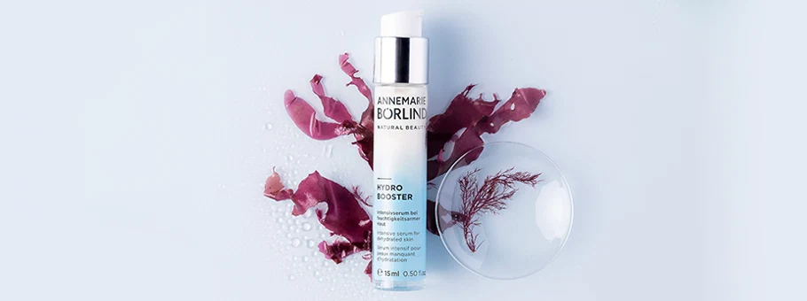 ANNEMARIE BÖRLIND HYDRO BOOSTER Serum mit Rotalge, Flasche vor roter Alge und Wassertropfen auf hellem Hintergrund