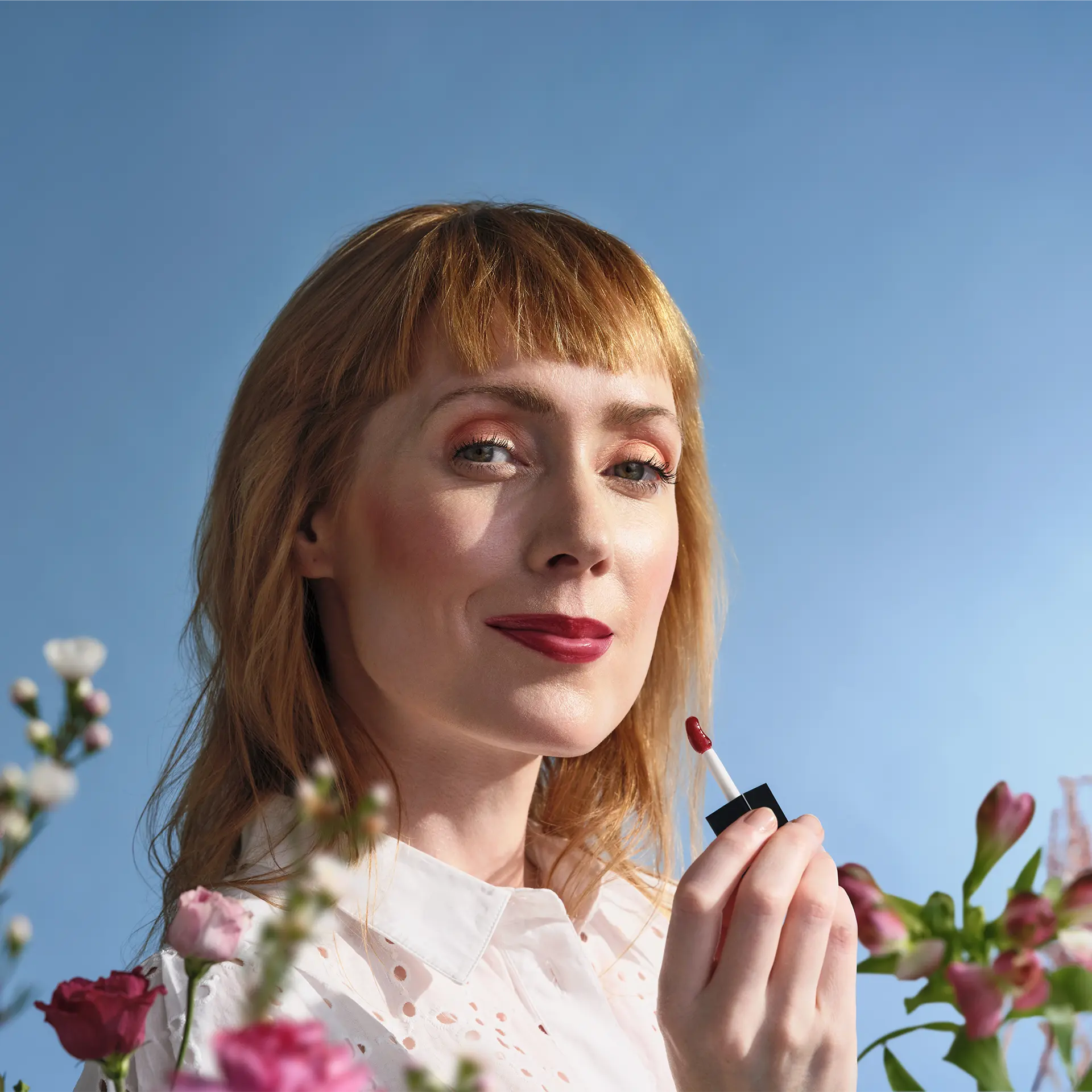 ANNEMARIE BÖRLIND Lip Oil Wild Fuchsia vor Gesicht einer Frau mit hellorangenen Haaren