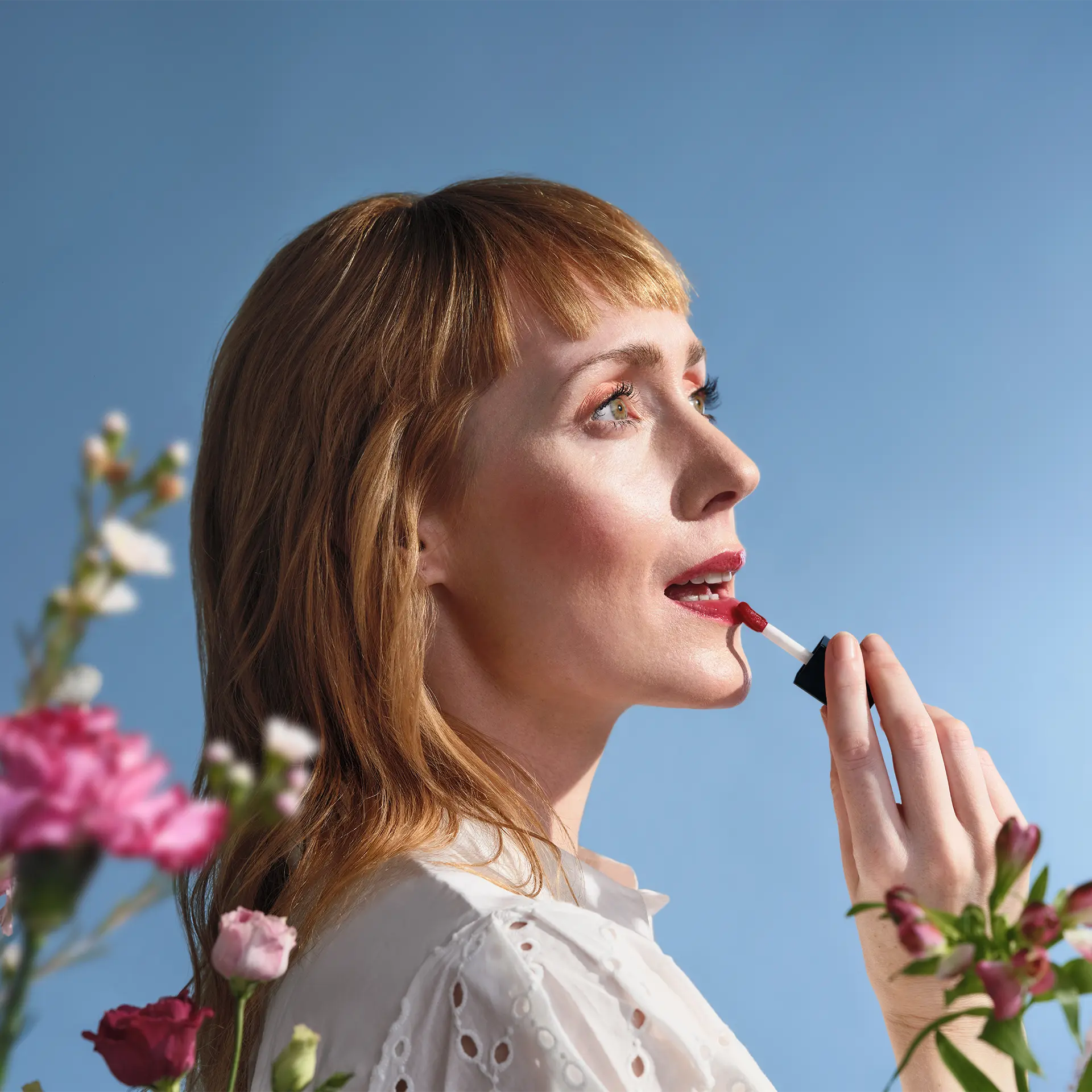 ANNEMARIE BÖRLIND Lip Oil Wild Fuchsia vor Gesicht einer Frau mit hellorangenen Haaren