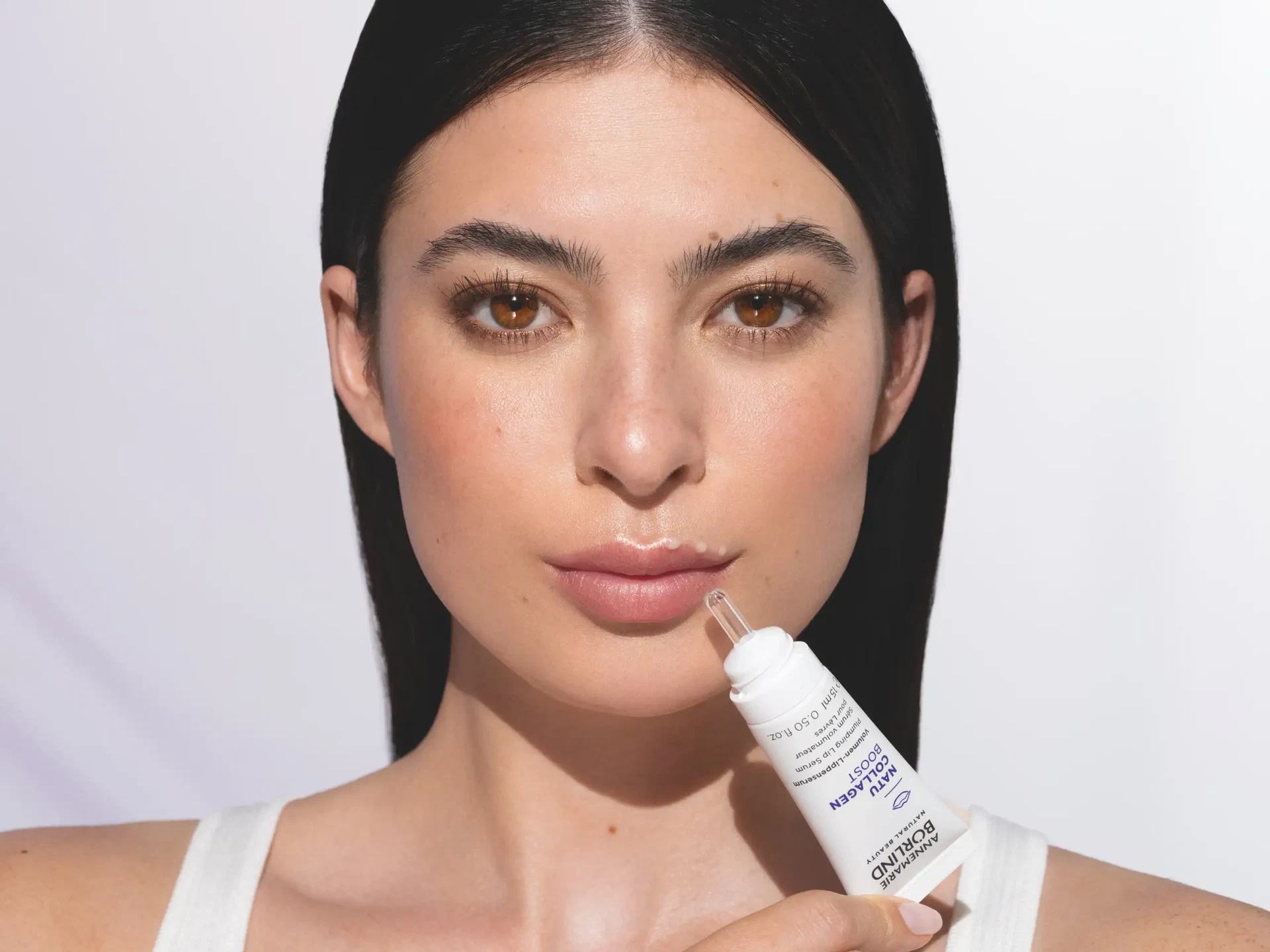 Frau trägt ANNEMARIE BÖRLIND NATU COLLAGEN Volumen-Lippenserum mit Pipette auf die Lippen auf