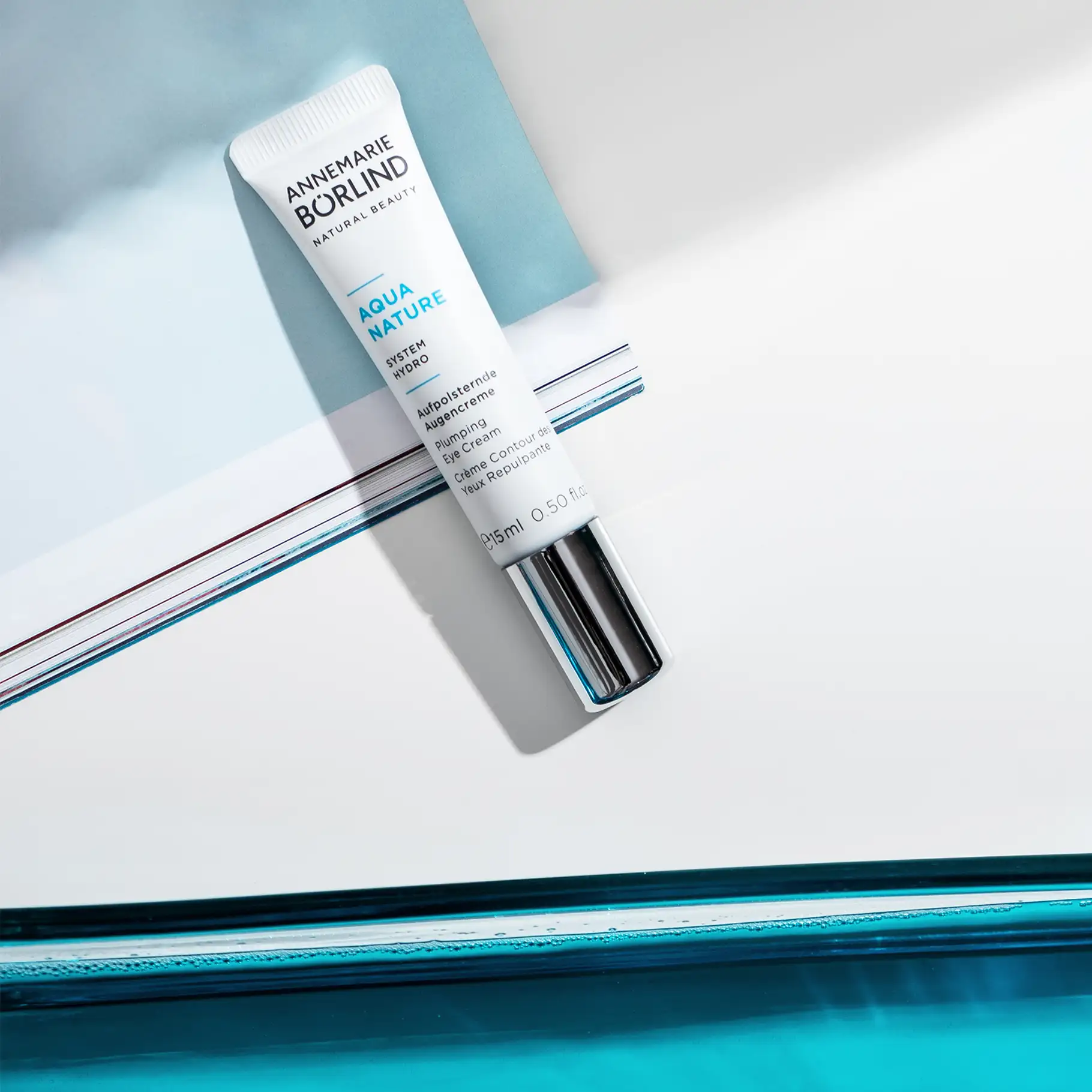 ANNEMARIE BÖRLIND AQUA NATURE aufpolsternde Augencreme in weißer Tube mit silbernem Verschluss auf blau-weißem Untergrund