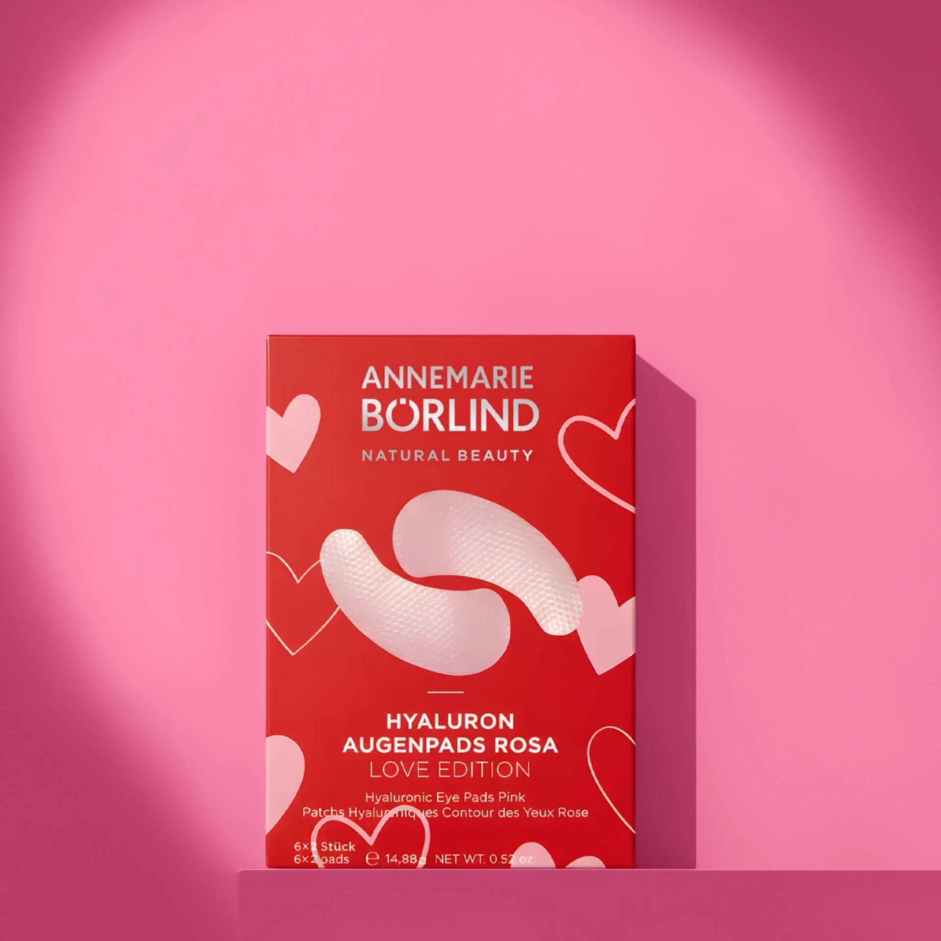 ANNEMARIE BÖRLIND Hyaluron Augenpads Love Edition in rot mit rosa Herzen, 6x2 Stück, vor rosa Hintergrund
