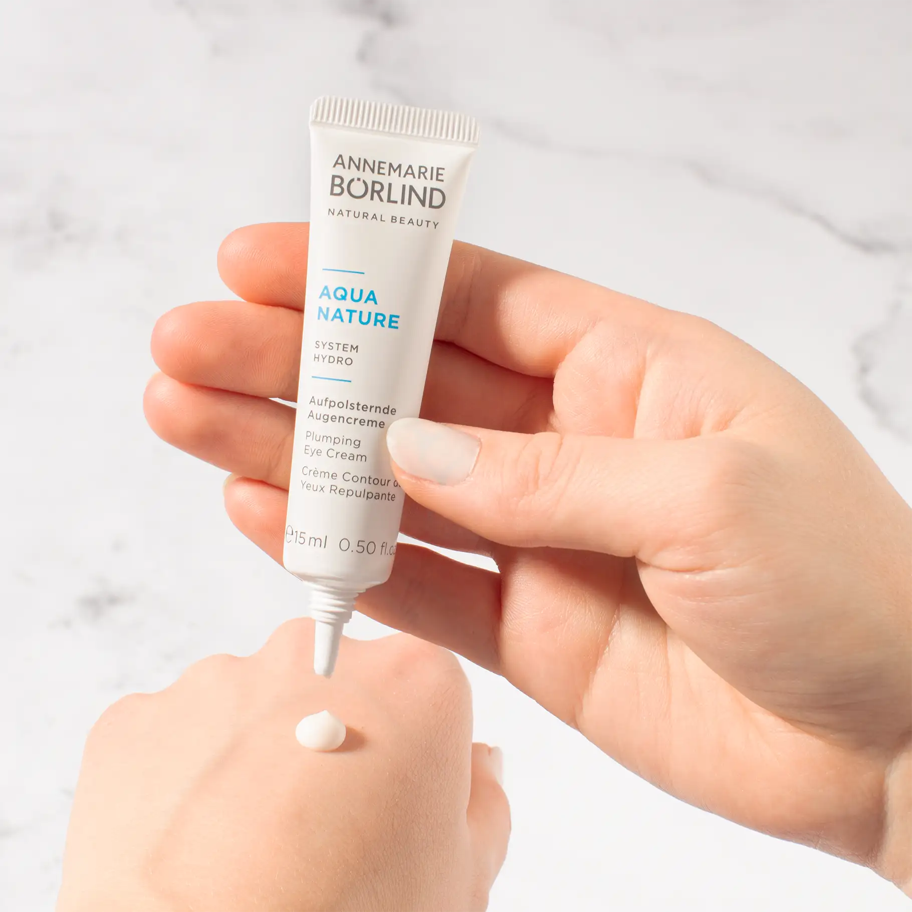 ANNEMARIE BÖRLIND AQUA NATURE aufpolsternde Augencreme in Hand mit Creme-Tropfen auf Haut