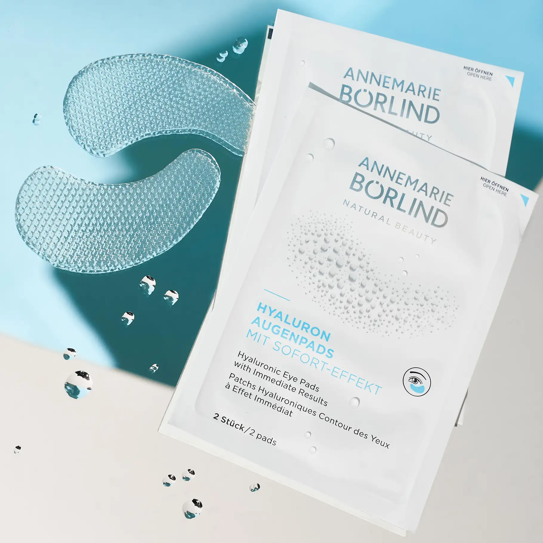 ANNEMARIE BÖRLIND Hyaluron Augenpads mit Sofort-Effekt, zwei Pads und zwei Sachets auf blauem Hintergrund